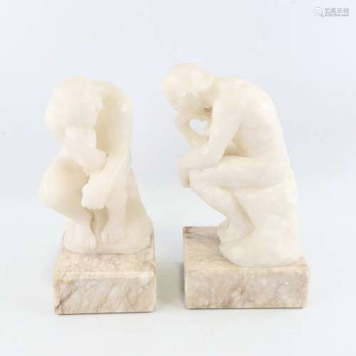 A pair of carved alabaster crouching figures on marble block...