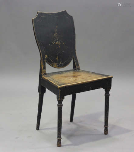 A late George III black painted walnut hall chair, the shiel...