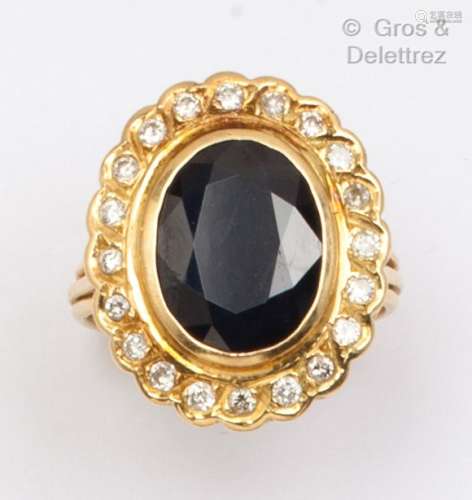 黄金戒指，在一圈明亮式切割钻石中镶嵌一颗椭圆形蓝宝石。手指大小...