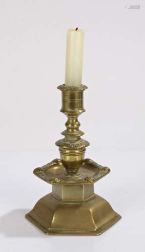 Brass candlestick, with a stepped stem and faces to the scon...