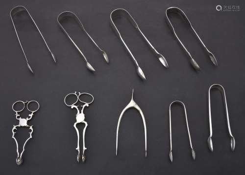 A collection of silver sugar tongs and nips