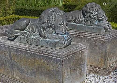 A pair of patinated bronze models of recumbent lions