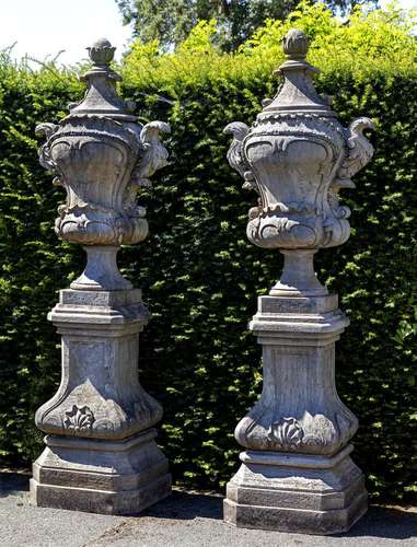 A pair of carved limestone garden urns on plinths