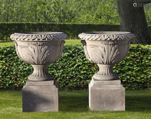 A pair of substantial carved limestone urns on plinths