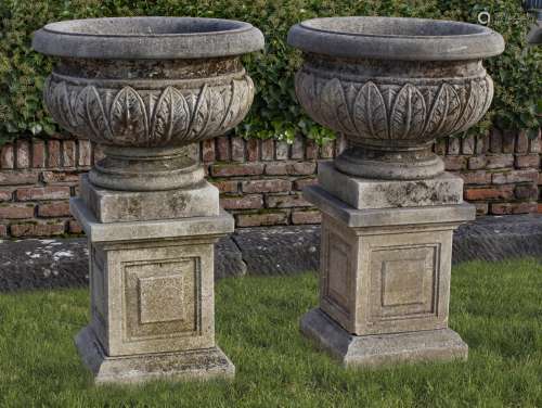A pair of Continental carved limestone urns on plinths