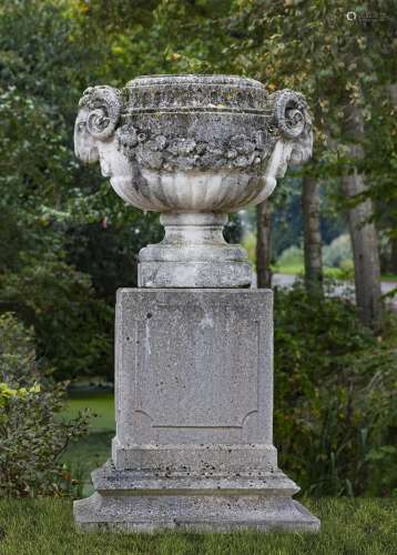 A stone composition twin handled garden urn on plinth