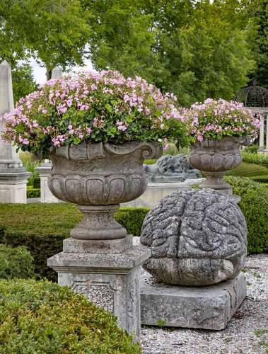 A pair of continental carved limestone garden urns on plinth...