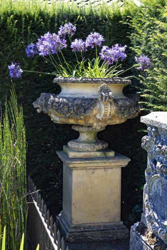 A stone composition garden urn on plinth, in Edwardian taste