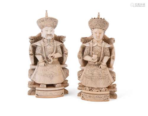 Y A pair of Chinese ivory figures modelled as a seated offic...