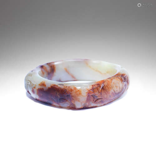 A PALE CELADON AND RUSSET JADE 'THREE RAMS' BANGLE Qing Dyna...