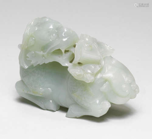 A RARE PALE GREEN JADE CARVING OF A QILIN CARRYING THE HEAVE...