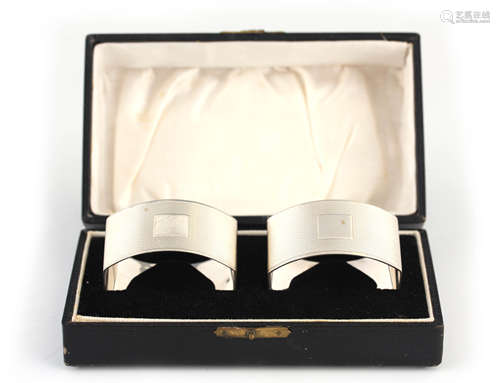 A CASED PAIR OF GEORGE V CHEQUERED SILVER NAPKIN RINGS with ...