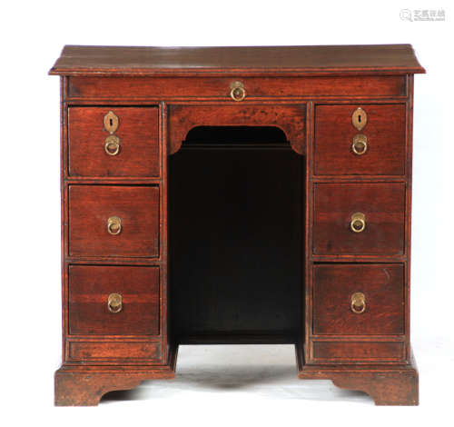 A QUEEN ANNE OAK KNEEHOLE DESK the moulded edge top above a ...