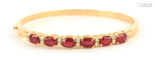 AN 18CT YELLOW GOLD RUBY AND DIAMOND HINGED BANGLE having si...