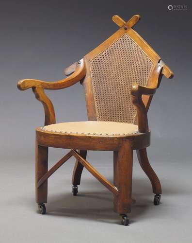 An Arts and Crafts walnut and caned armchair, the shaped and...