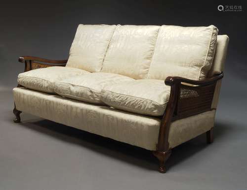 An Edwardian mahogany and caned three seat sofa, upholstered...