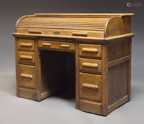 An oak cylinder kneehole desk, with tambour top, enclosing t...