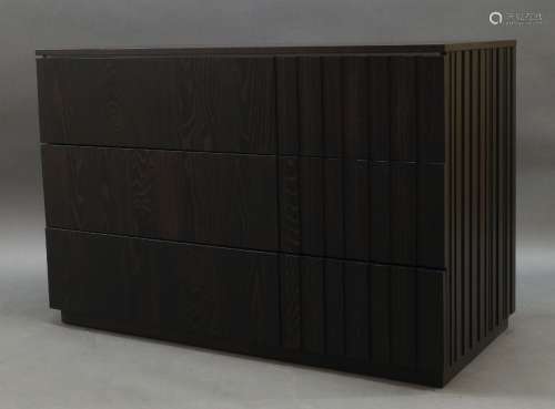 A contemporary stained wood chest of drawers, with three dra...