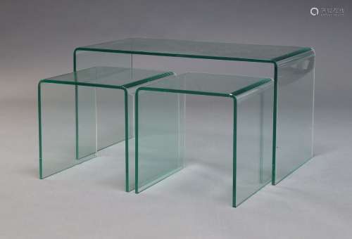 A contemporary set of nesting glass side tables, each formed...