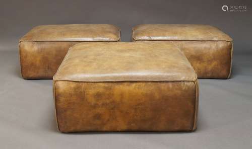 A set of three large leather upholstered poufs, of recent ma...