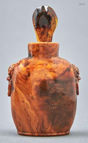 A Chinese amber snuff bottle, 20th c, carved with mask and r...