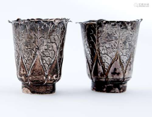 A pair of Chinese miniature silver beakers of lobed and leaf...