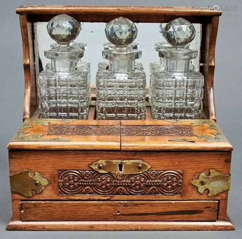 A Victorian oak tantalus, with silver plated strapwork mount...