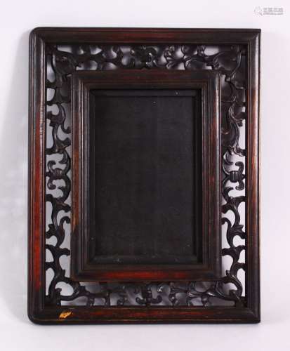 A CHINESE CARVED HARDWOOD FRAME, carved with openwork of flo...