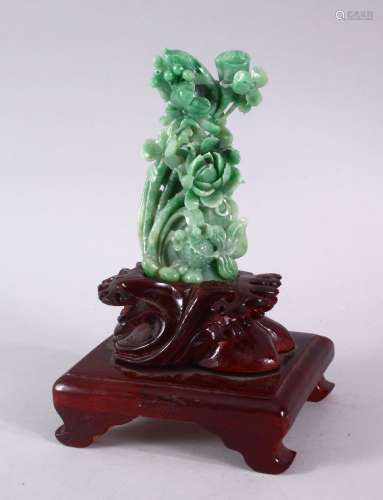A GOOD GREEN JADITE CARVING OF FLOWERS, 13cm high, on a carv...