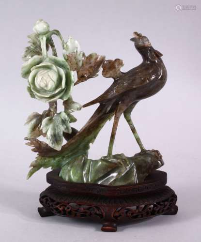 A CHINESE CARVED JADEITE FIGURE OF A PEACOCK & FLORA, the pe...