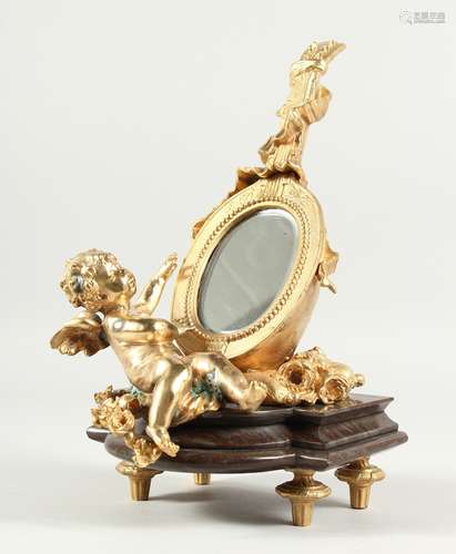 A GILT BRONZE CUPID MIRROR on a marble base. 12ins high.