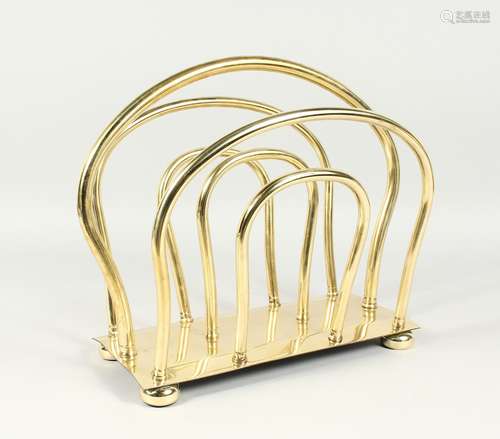 AN EDWARDIAN BRASS TWO DIVISION MAGAZINE RACK on ball feet. ...