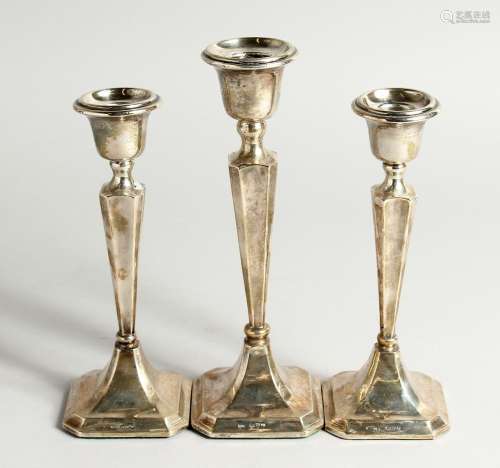 A SET OF THREE SILVER CANDLESTICKS with loaded bases. Cheste...