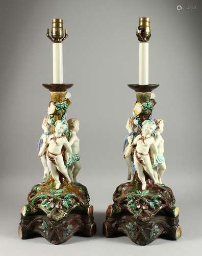 A LARGE PAIR OF MAJOLICA POTTERY LAMPS,with three cupids aro...