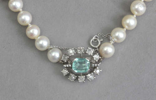 A cultured pearl necklace with an emerald and diamond brooch...
