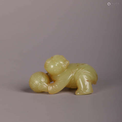 A Yellow Jade Carving Of A Child Playing Ball