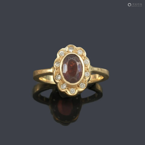 Ring with oval cut garnet and diamond border in 18K