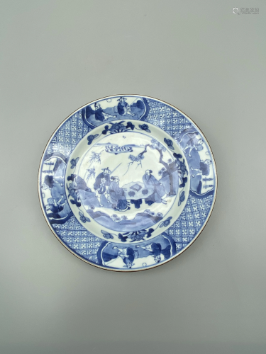 A blue and white plate, decorated with figures playing