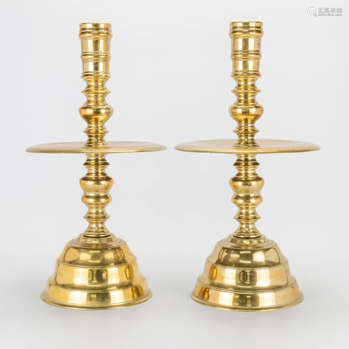 A pair of large and antique bronze disk candlesticks.