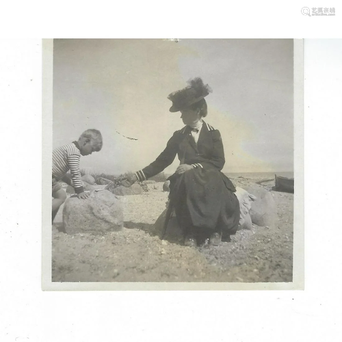 Photo of a small boy & woman in large hat on the beach