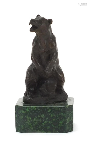 Patinated bronze bear raised on a square green marble