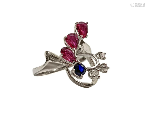 White gold ring with three rubies, one sapphire blue