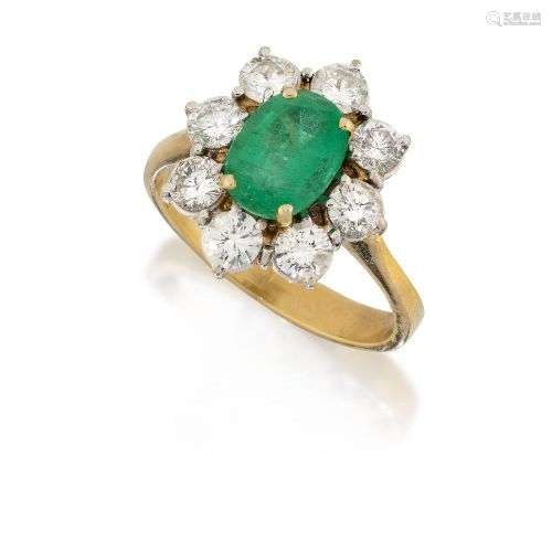 An emerald and diamond cluster ring, the oval emerald within...