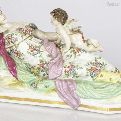 A porcelain statuette of a lady in a floral dress and a putt...