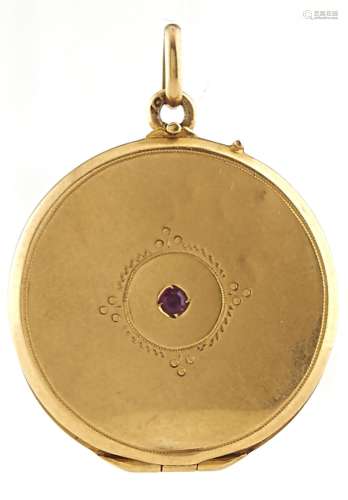 A gold locket set with a central ruby, marked 18ct, 4.6g