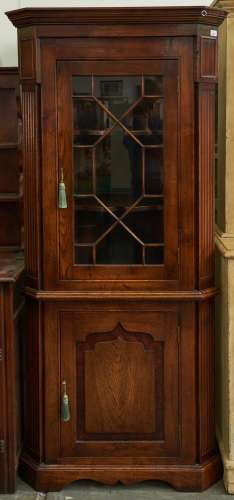 An antique style oak glazed corner cupboard, the lower part ...
