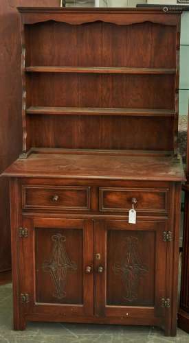 A panelled oak dresser and rack, the lower part with carved ...