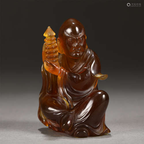 An Amber Carved Figure Holding A Pagoda