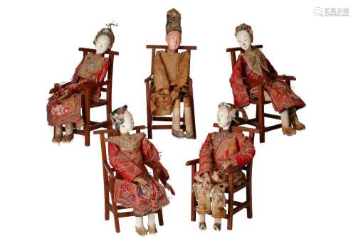 Five Chinese dolls in silk clothes on wooden chairs, four la...