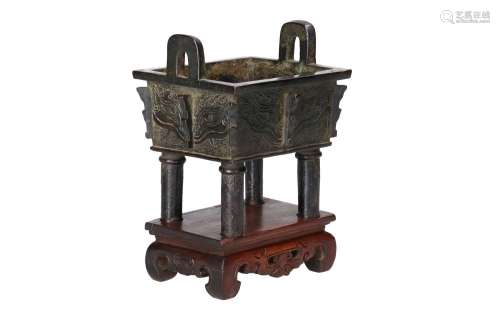 A bronze incense burner with two handles on carved wooden ba...